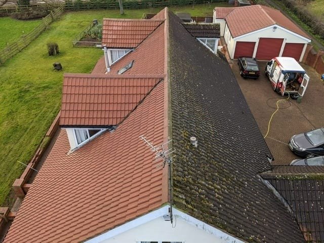 Vue aérienne d’une toiture en cours de démoussage : un versant nettoyé, l’autre encore couvert de mousse