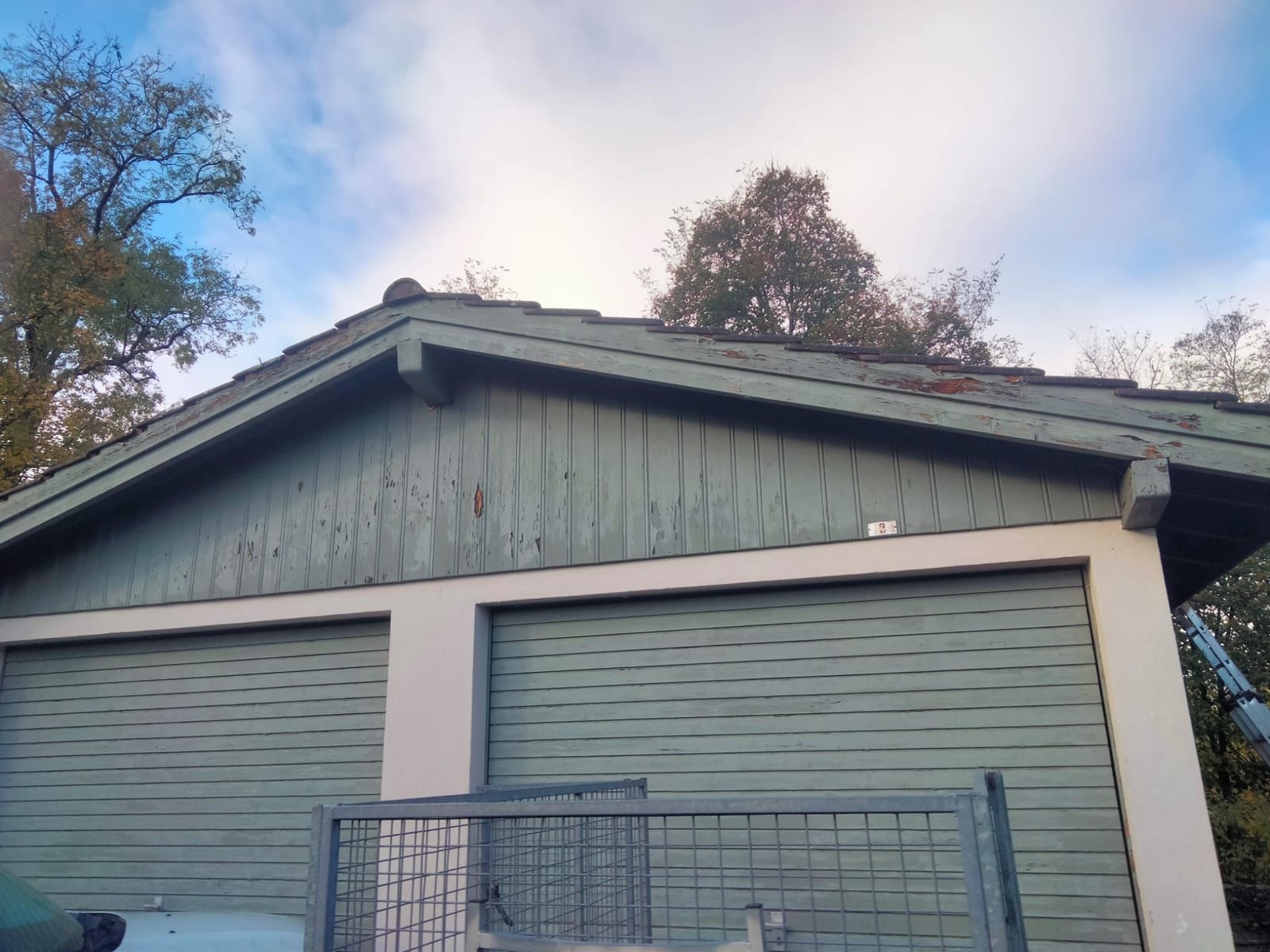 Pignon en lames de bois et portes de garage à la peinture très écaillée