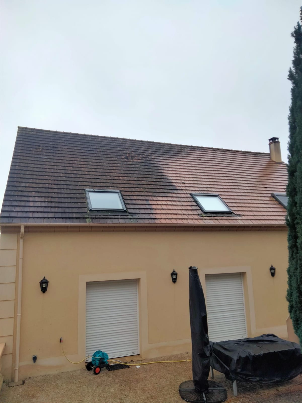 Versant de toiture en tuiles montrant une démarcation nette entre la partie noircie par les mousses et la partie nettoyée