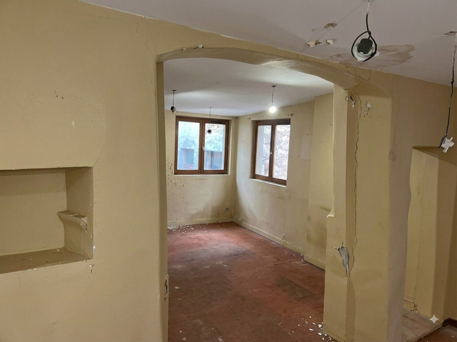 Pièce intérieure avec arcade, murs et plafond abîmés et écaillés avant travaux