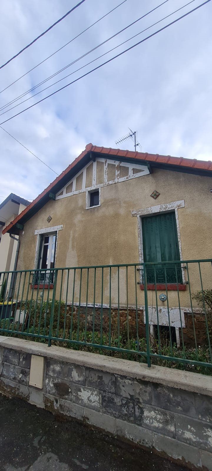 Pignon de maison aux faux colombages et encadrements de fenêtres écaillés, façade encrassée, avant travaux